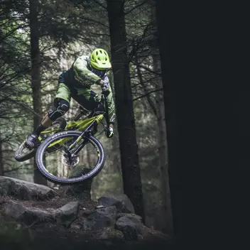 Bike Style - Graphic showing mountain biker jumping over rocks doing a trick in a dark wooded forest (1)